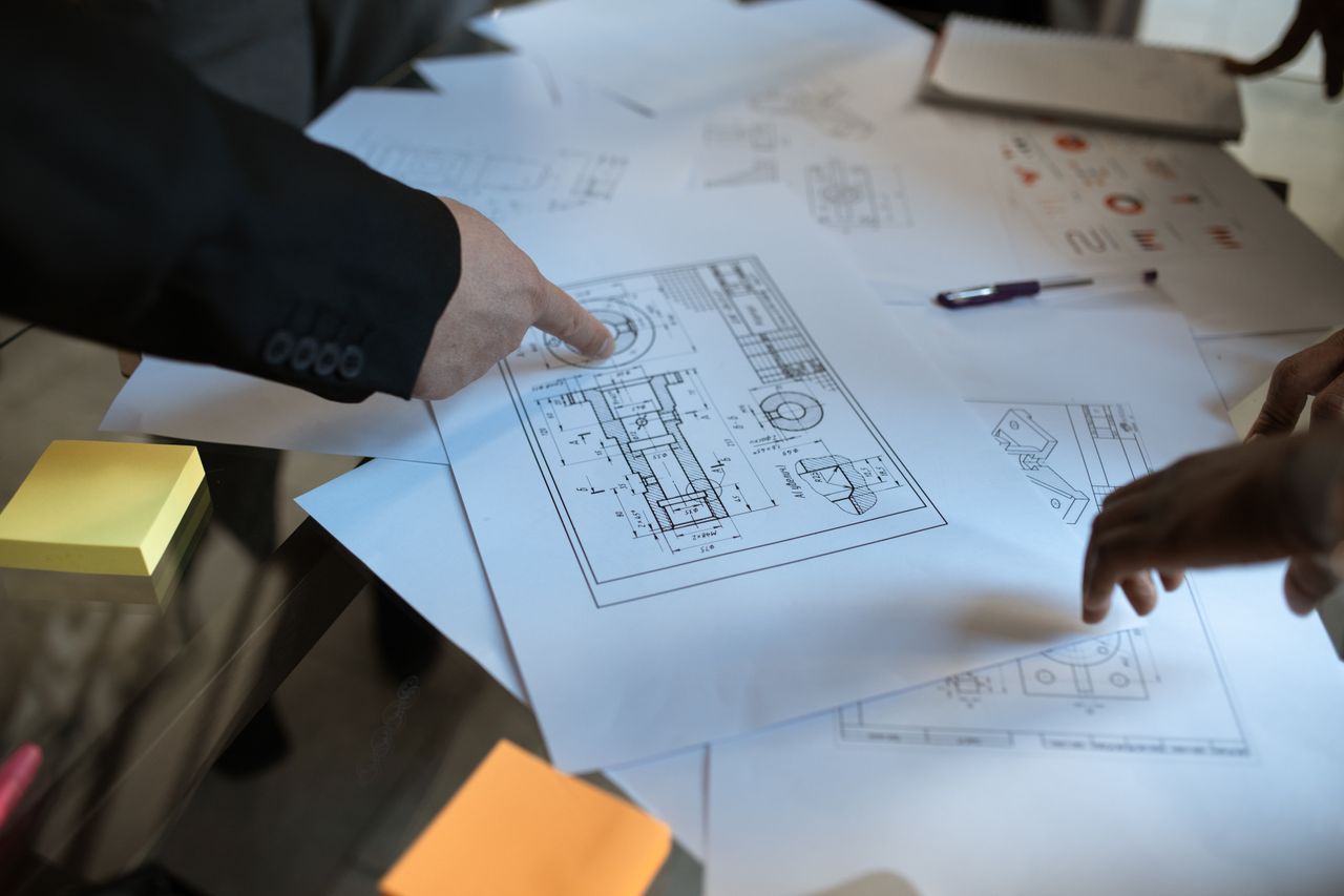 Mastering the First Impression: Your intriguing post title goes here Engineers discussing blueprints at a workspace, focusing on teamwork and architecture design.